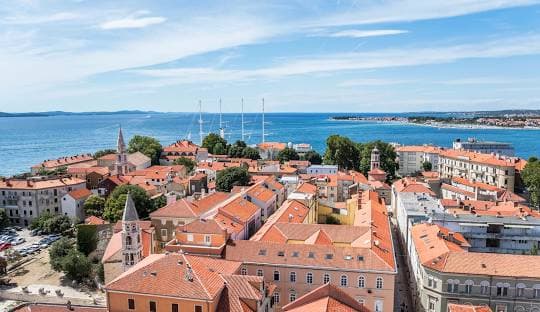Zadar old town rooftops and harbour with sailing yachts offshore